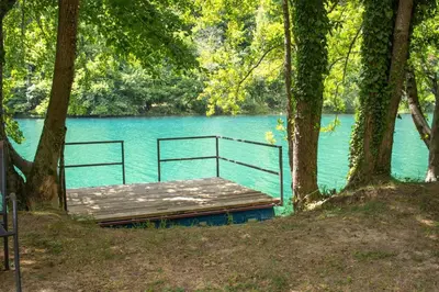 a wooden bench sitting in front of a body of water at Natura na Uni in Bihać
