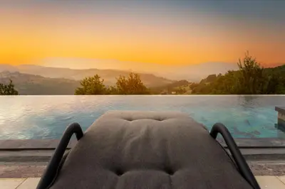 a chair in front of a swimming pool with a sunset at Green Sea Resort - Zeleno More in Visoko