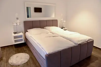 a large bed in a room with two night stands at Apartmani i Bungalovi TROJKA in Banja Luka