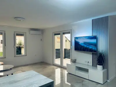 a living room with a flat screen tv on a wall at Apartman Zen in Bihać