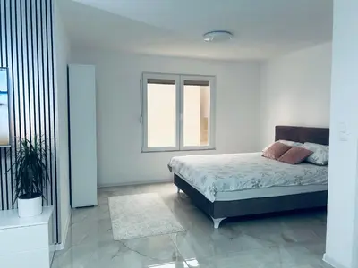 a white bedroom with a bed and a window at Apartman Zen in Bihać