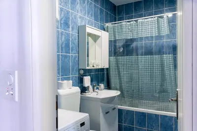 a blue tiled bathroom with a sink and a shower at Apartman Rest 'n' Go in Doboj