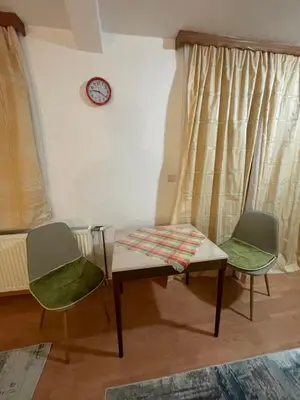 a room with two chairs and a table and a clock at Apartmani Centar Fojnica in Fojnica