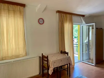 a dining room with a table and a clock on the wall at Apartmani Centar Fojnica in Fojnica