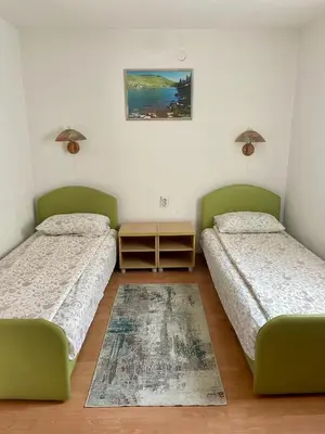 a room with two beds and a table at Apartmani Centar Fojnica in Fojnica