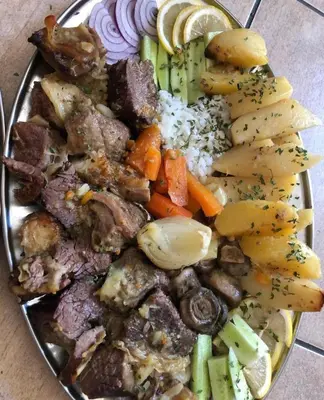 a plate of food with meat and vegetables on a table at Sobe Dado, Gostionica Kod Dade in Banja Luka