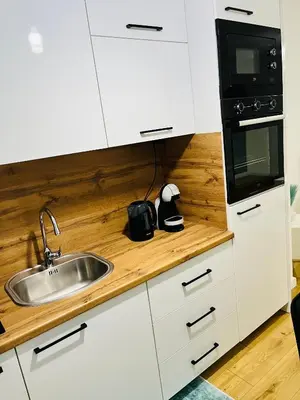 a kitchen with white cabinets and a sink and a microwave at LookView apartment in Bihać