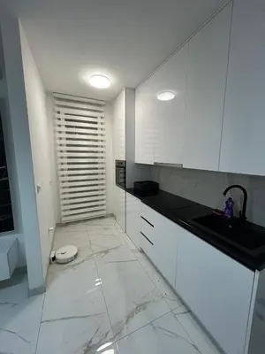 a kitchen with white cabinets and a tile floor at Apartman City Centar Banjaluka in Banja Luka