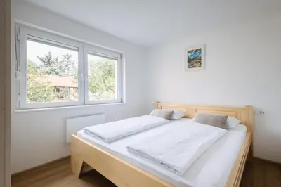 a bedroom with a bed with white sheets and a window at BDD House in Banja Luka