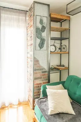 a living room with a green couch and a brick wall at Šarmantan stan u centru grada in Banja Luka