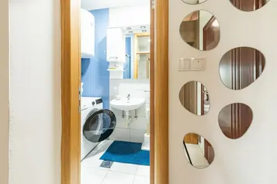 a bathroom with a washing machine and mirrors at Šarmantan stan u centru grada in Banja Luka