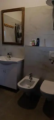 a bathroom with a sink and a toilet and a mirror at Apartman Bihać SviMi in Bihać