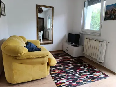 a yellow chair in a living room with a mirror at Apartman Bihać SviMi in Bihać
