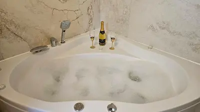 a bath tub with a bottle of champagne and two wine glasses at Vila Mir in Banja Vrućica