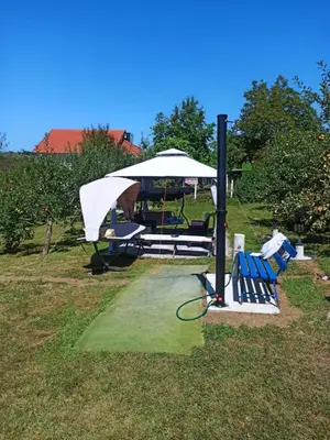 a picnic table with a white umbrella and benches at Retro Retreat Izačić in Bihać