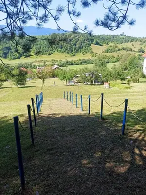 a rope fence in a field with a hill in the background at Retro Retreat Izačić in Bihać