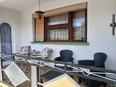 a balcony with chairs and a table and a window at Retro Retreat Izačić in Bihać
