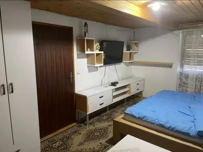 a bedroom with a bed and a desk with a tv at Vila Ponijeri in Kakanj