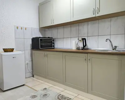 a kitchen with white cabinets and a microwave and a refrigerator at Vista in Živinice