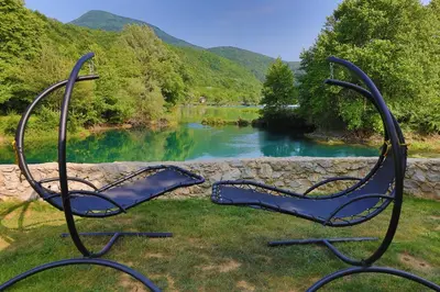 a couple of chairs sitting in the grass next to a river at Holiday Homes Mujo Bejzin in Račić