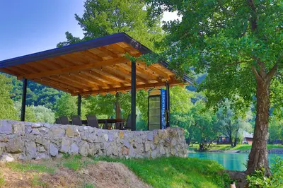 a pavilion with a table and chairs on a stone wall at Holiday Homes Mujo Bejzin in Račić