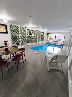 a swimming pool in a room with a table and chairs at Villa Casa de Dina in Bihać