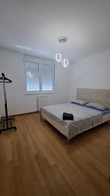 a white bedroom with a bed and a wooden floor at Apartman Giro in Banja Luka