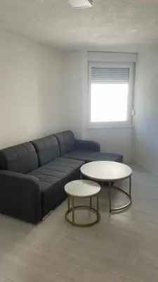 a living room with a blue couch and two tables at Apartman Magi in Jajce