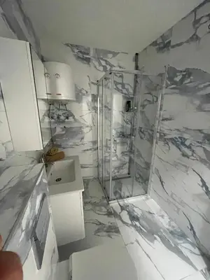 a marble bathroom with a shower and a sink at Apartman Magi in Jajce