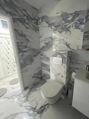 a bathroom with a toilet and a marble wall at Apartman Magi in Jajce