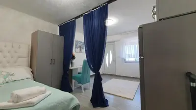 a bedroom with a bed and a blue curtain at Studio Apartman Mint Bihac in Bihać