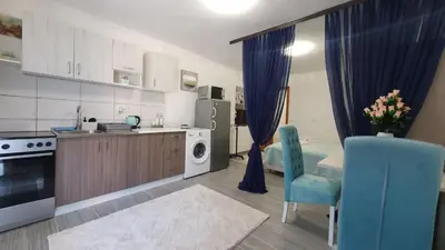 a kitchen with a blue chair and a table and a microwave at Studio Apartman Mint Bihac in Bihać