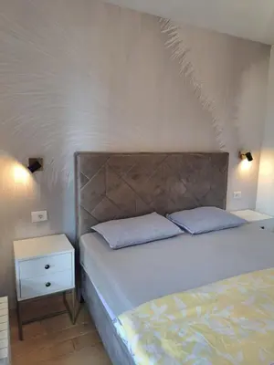 a bedroom with a bed and a white wall at Premier Apartment in Banja Luka