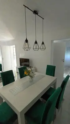 a dining room table with green chairs and three lights at 