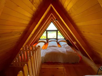 a bed in a wooden room with a window at BellaVista Prokosko Jezero in Paljike