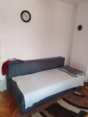 a bed in a room with a clock on the wall at Apartment Miki in Visoko