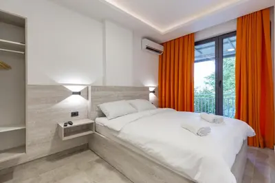 a bedroom with a large white bed with orange curtains at Apartments River in Visoko
