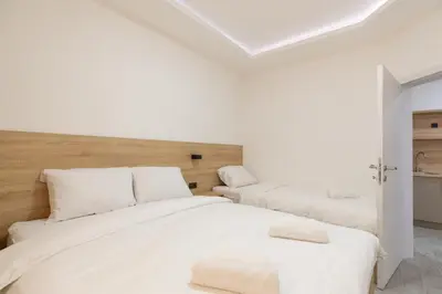 a white bedroom with two beds with white pillows at Apartments River in Visoko
