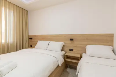 two beds in a hotel room with white sheets at Apartments River in Visoko