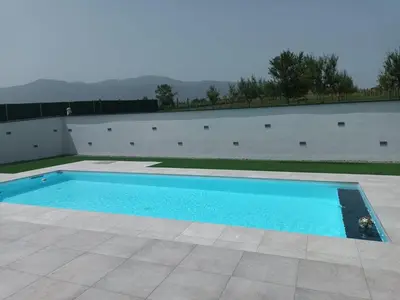 a swimming pool in front of a white wall at Vila Pascha in Zlopoljac