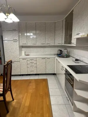 a kitchen with white cabinets and a wooden floor at Royal Apartment in Banja Luka