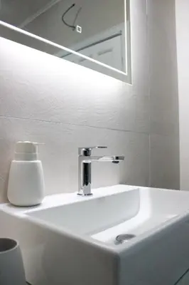 a bathroom sink with a mirror and a soap dispenser at Royal Apartment in Banja Luka