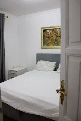 a bedroom with a white bed and a painting on the wall at Royal Apartment in Banja Luka