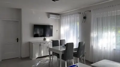 a white dining room with a table and chairs at Apartments Bioland in Kulen Vakuf