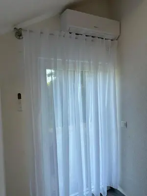 a window with white curtains in a room at Apartments Bioland in Kulen Vakuf