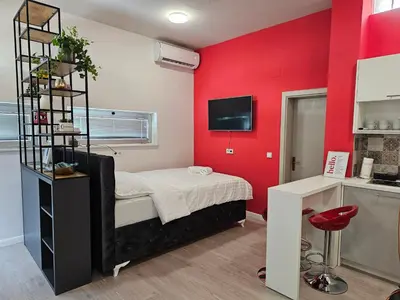 a bedroom with red walls and a bed and a desk at Apartmani EMA Bihać in Bihać