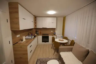 a kitchen and a living room with a couch and a table at Apartman Centar in Fojnica