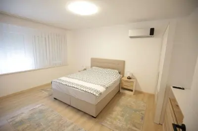 a white bedroom with a bed and a window at Apartman Centar in Fojnica