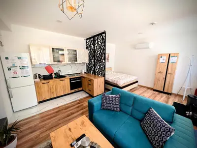 a living room with a blue couch and a kitchen at Apartmani Dinarika in Livno