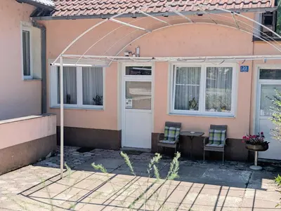 a pink house with two chairs and a white door at Apartmani Dinarika in Livno